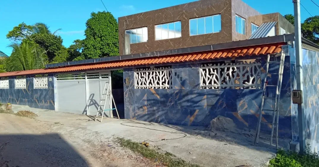Fachada residencial revestida com portão e cobertura