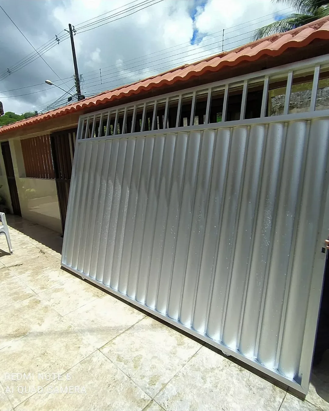 Portão metálico branco instalado em residência
